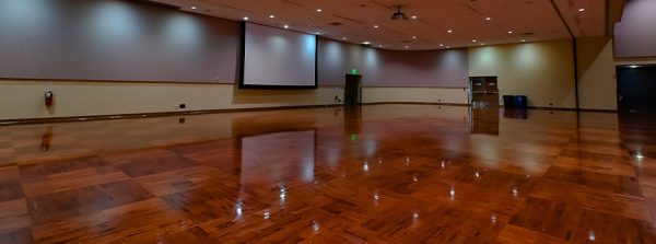 A picture of a ballroom with projector screen and hardwood floors.