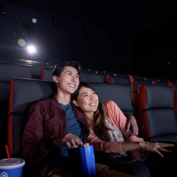 Couple sitting in Regal Live LA Stadium 14 theater enjoying a movie